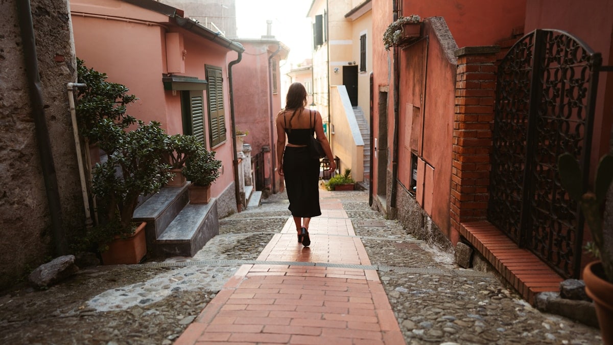 woman in black long sleeve shirt and black pants walking on sidewalk during daytime